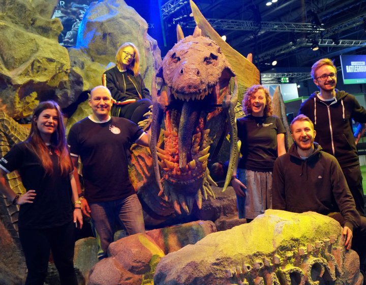 Falmouth University Games Academy students standing in front of a large dinosaur model