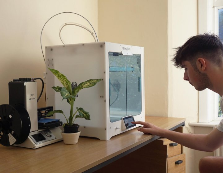 A Falmouth University Sustainable Product Design student with a 3D printer