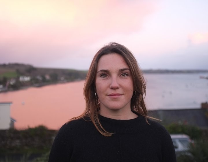 Head shot of graduate Jess Fairlie, with sea view in background