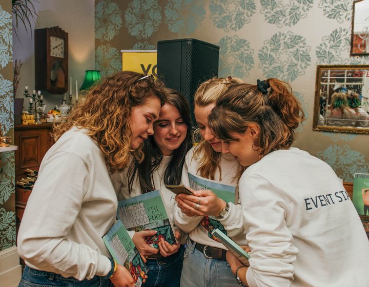 A group of Creative Event Management BA(Hons) students huddled round looking at a phone