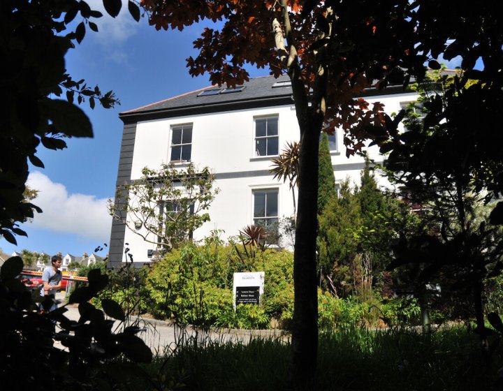 Exterior of period building on Falmouth campus surrounded by trees and greenery.