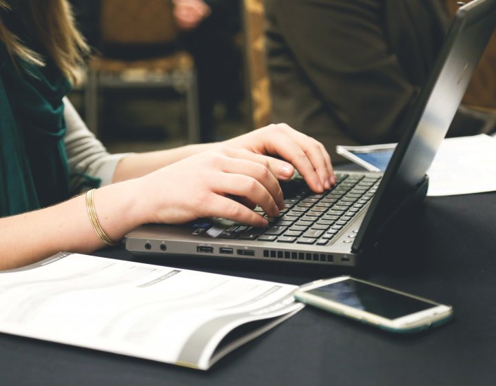 Woman studying at laptop with books and journals