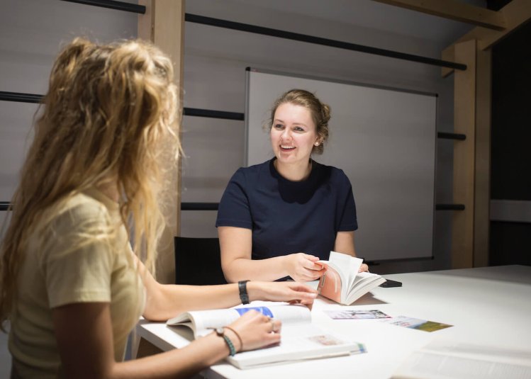 Two female Falmouth University students sat at a table with open books