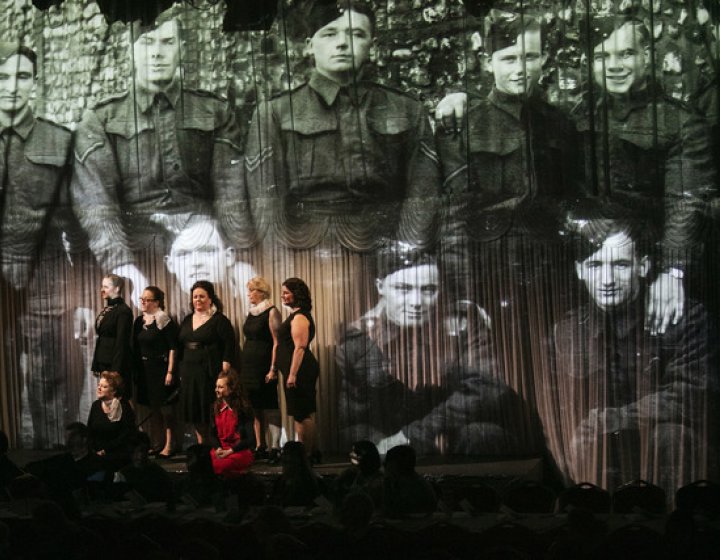 A group of women standing in front of a projection of soldiers