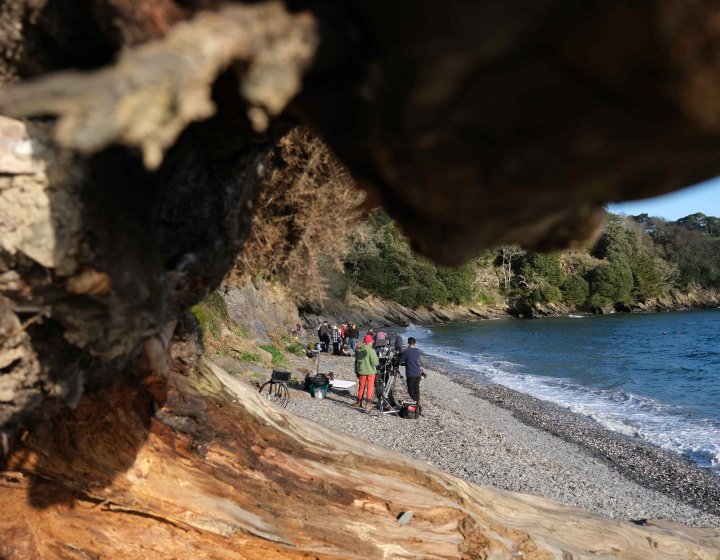 A group of students can be seen through the gap in a rock