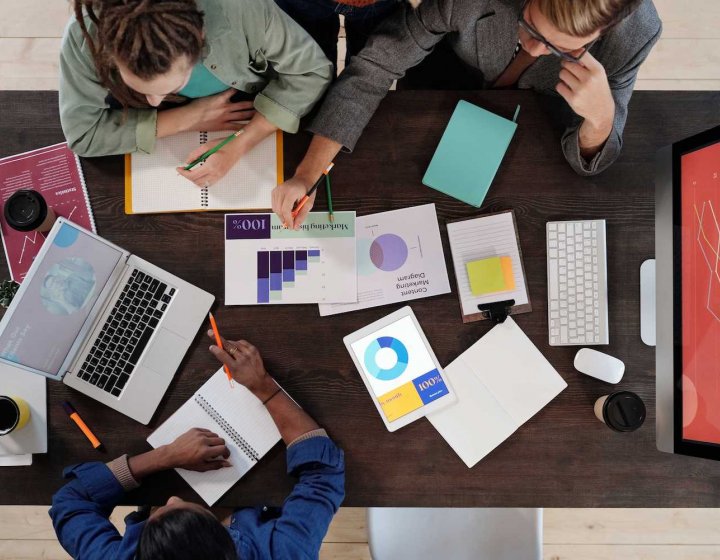 Three people sat at a table with graphs on paper