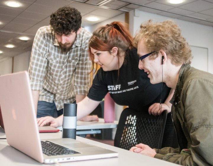 Three students around laptop