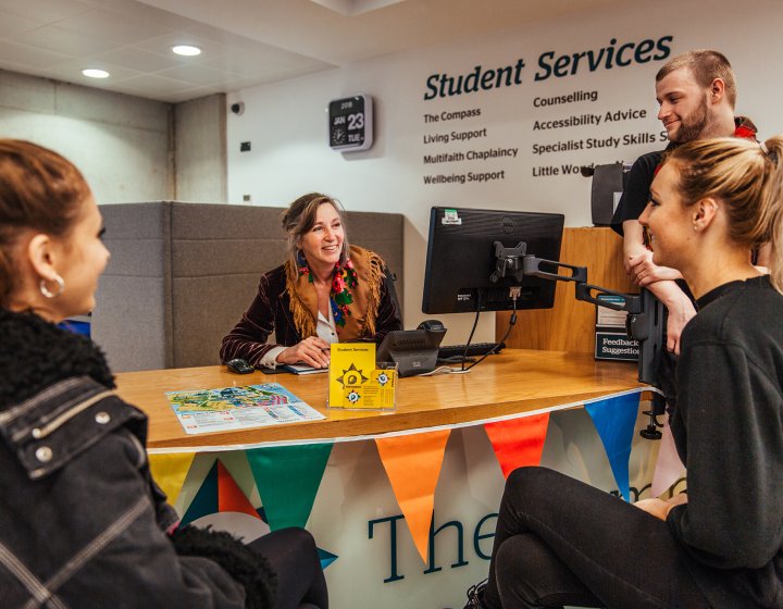 Staff and students discussing around a desk.