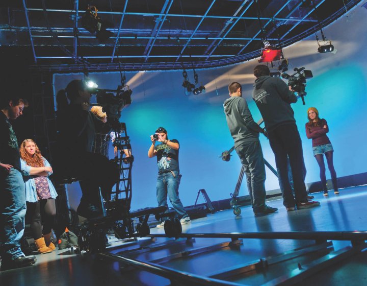 Students working in television studio lit up in blue at Falmouth University