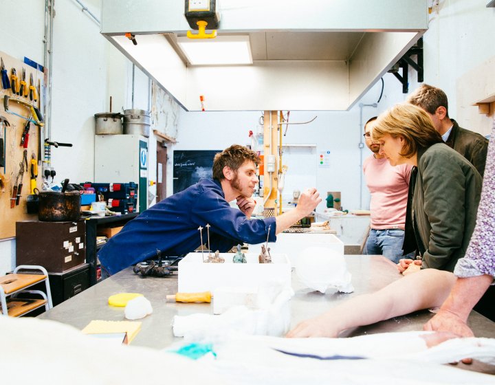 Falmouth University technician showing small object to three people in a workshop