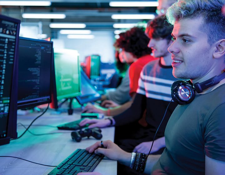 A student coding at a computer, wearing headphones