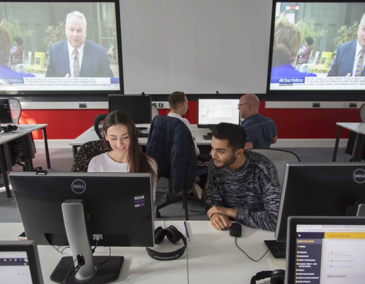 Two Falmouth University Journalism students working together at a computer
