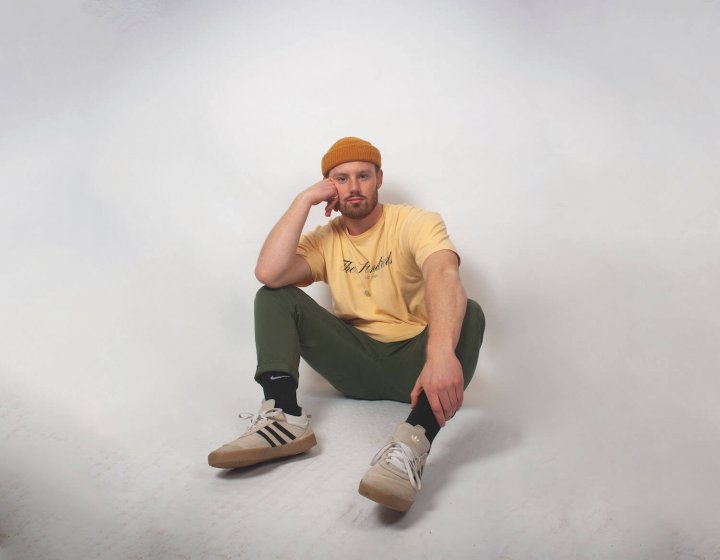 Sustainable Product Design student sitting on the floor wearing an orange hat and yellow tshirt