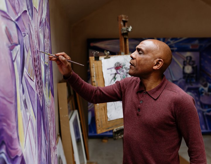 Denzil Forrester painting on a canvas in his studio