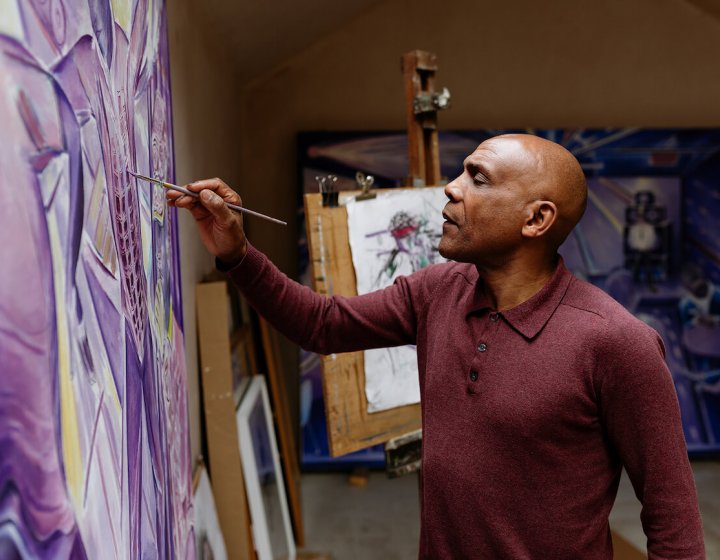 Denzil Forrester painting on a canvas in his studio