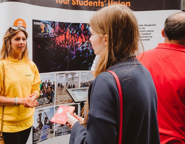 A Falmouth University student ambassador talking to a girl wearing a navy jacket
