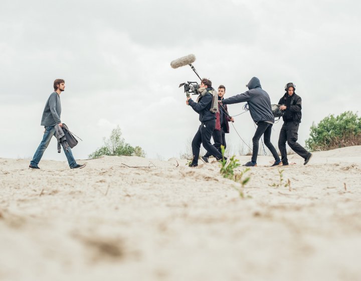 Students man cameras and lighting equipment on the set of Origin