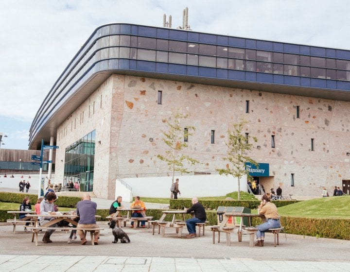 People and benches outside the Stannary buidling on Penryn campus.