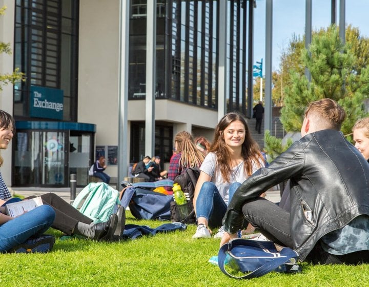 Penryn campus students outside exchange, sitting on grass