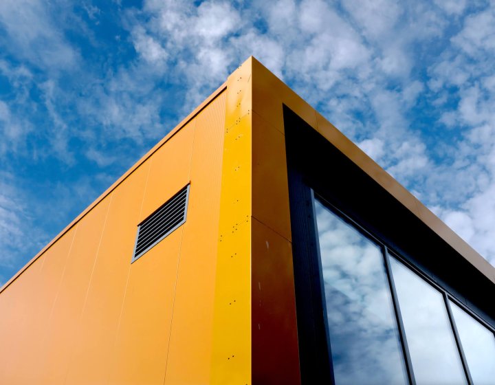 Orange and black Penryn Campus Sports Hall building with blue sky in the background