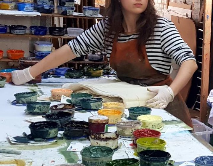 A girl in a studio surrounded by paint pots