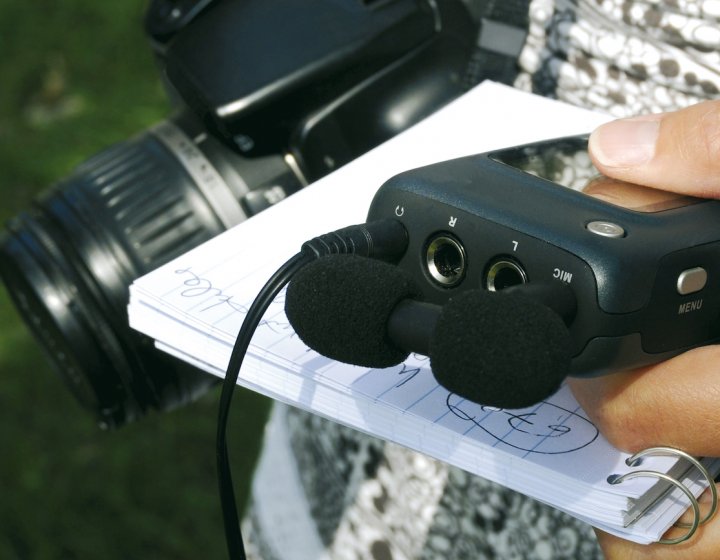 Close up of dictaphone, notepad and SLR camera