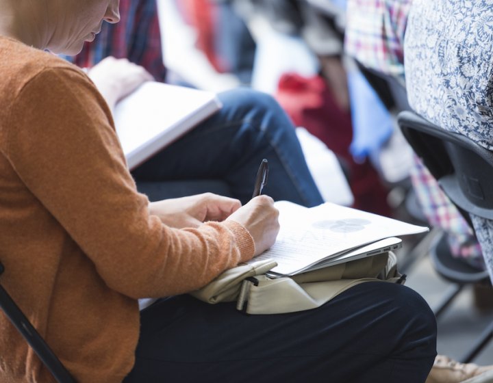 A woman seated writing in her notebook