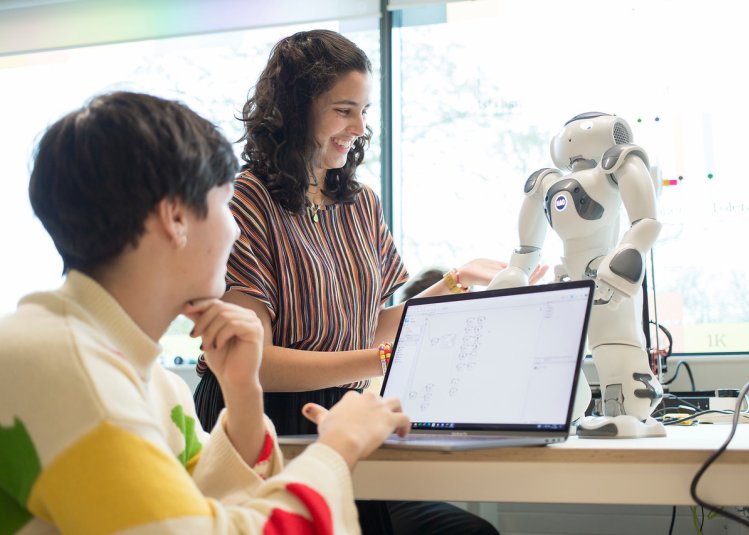 Two Robotics students operating a small robot with a laptop