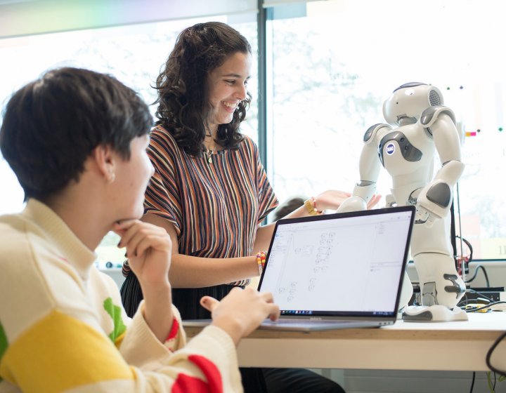 Two Robotics students operating a small robot with a laptop