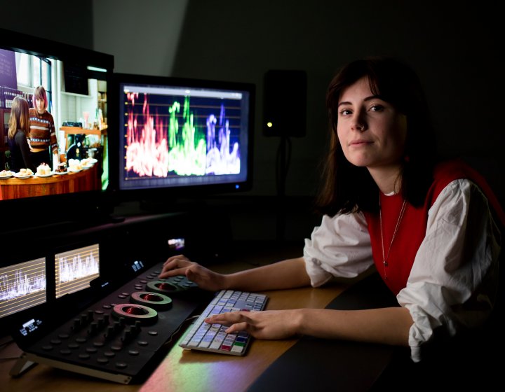 Student at editing desk with several screens in front of her.