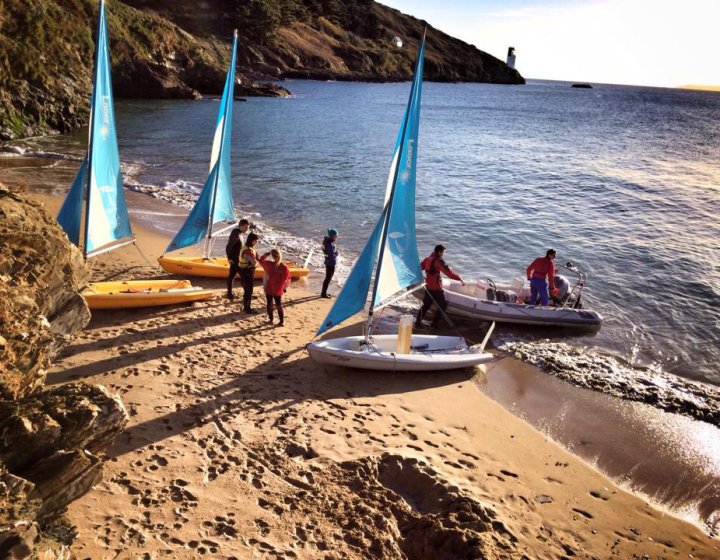 Falmouth University students on a beach with sailing dinghies