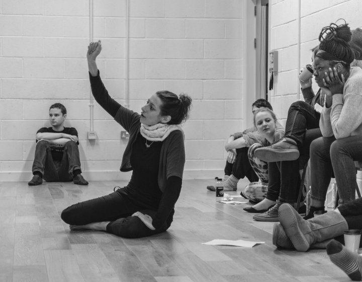 Falmouth University Acting student sitting down with her arm raised above head