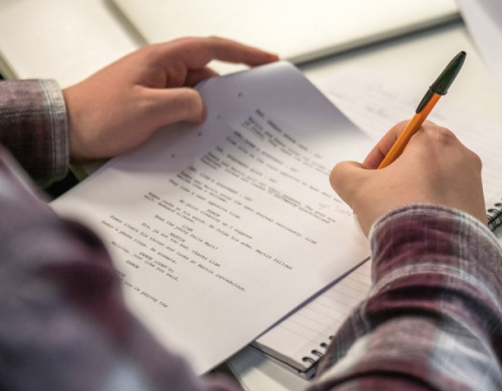 Hands holding a script and annotating it with a pen