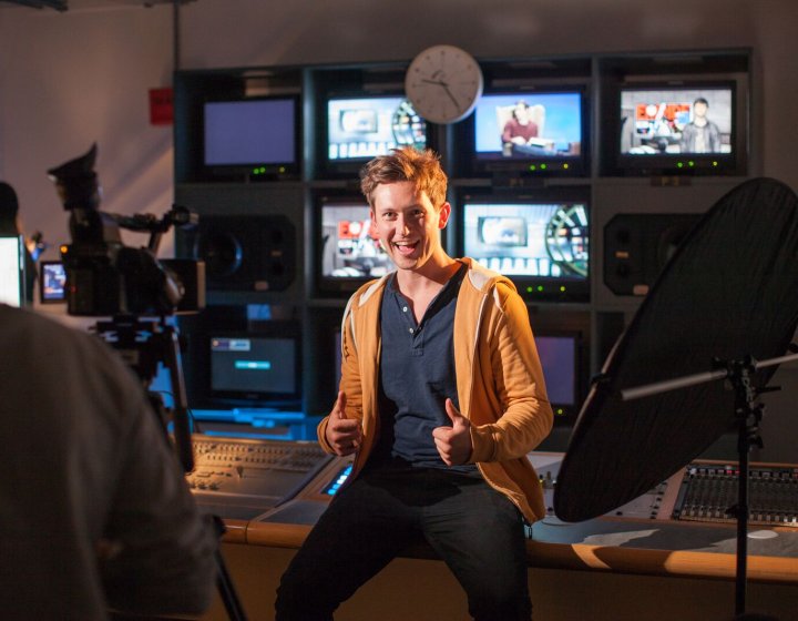 Student giving the thumbs up in television control studio.