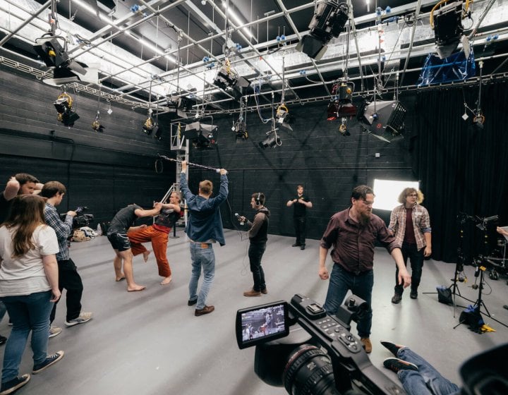Film students combat fighting and filming in a studio.