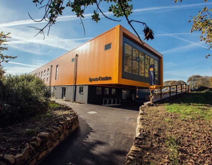 Falmouth University Sports Centre building exterior with blue sky and a path