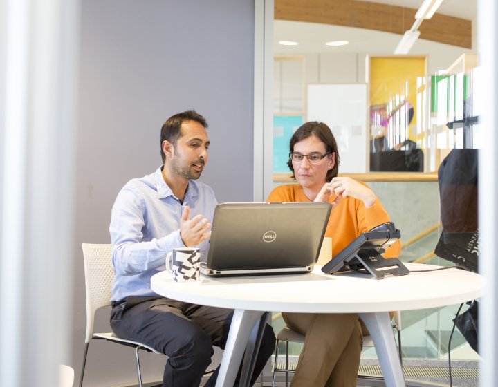 Staff looking at a laptop and gesturing with hand.