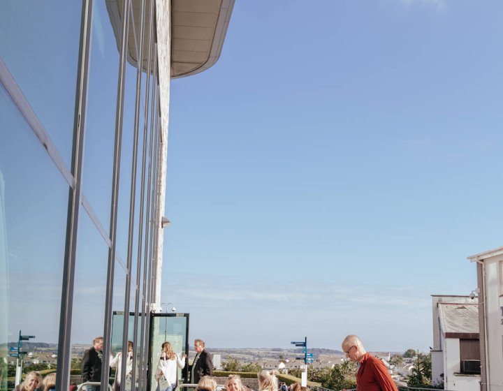 People sat at benches outside with a glass building to the right