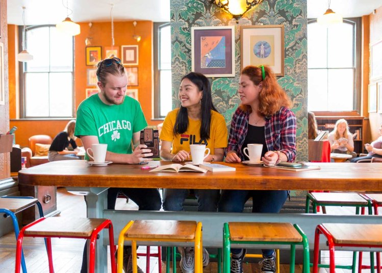 Brightly dressed Falmouth students having coffee in brightly decorated cafe.