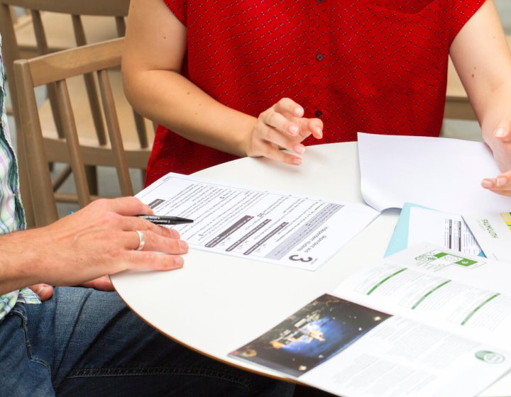 Hands on a white table with a range of documents