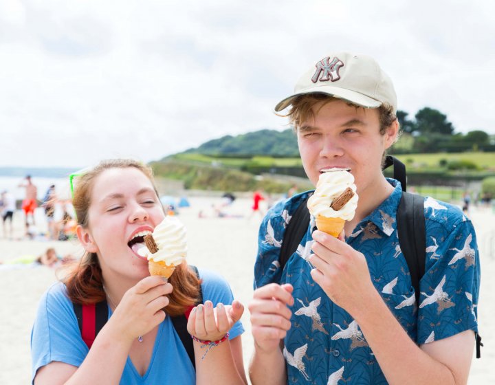 Two Falmouth University students eating ice creams on the beach