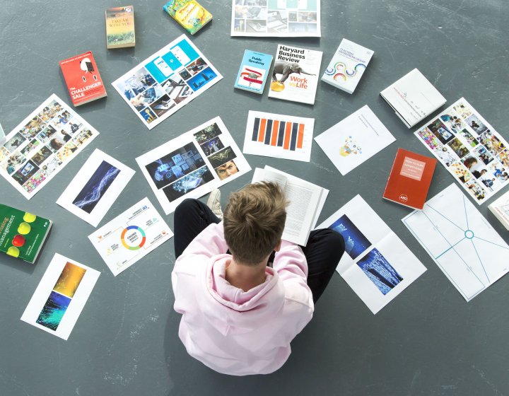 A Falmouth University student sat on the floor surrounded by papers and books