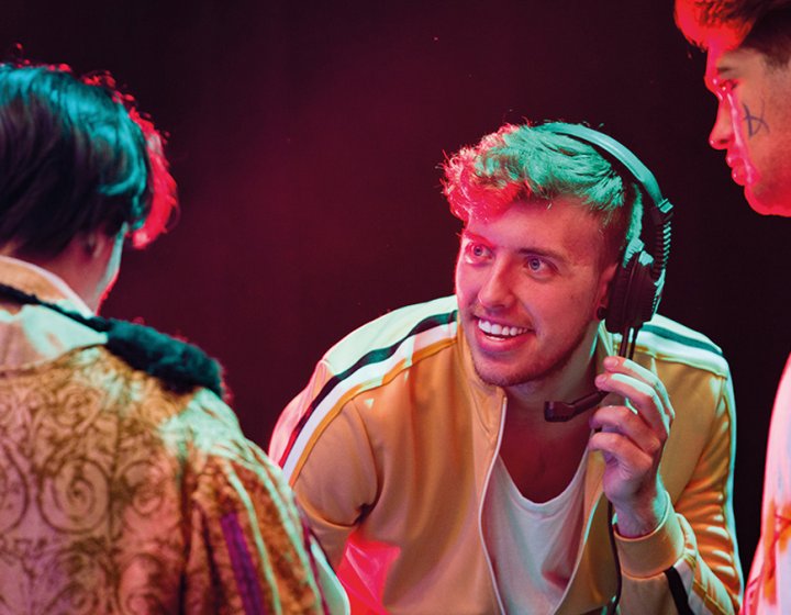 Technical Theatre Arts student wearing a headset while talking to two other students