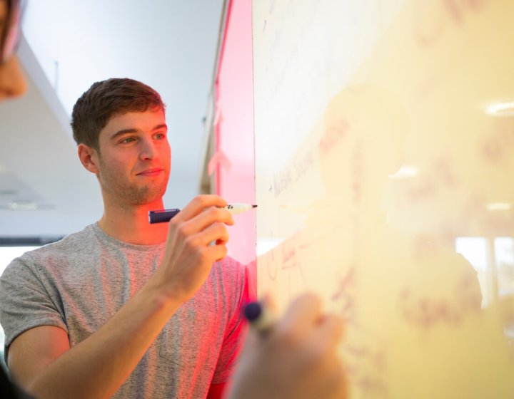 Falmouth University business student writing on a white board