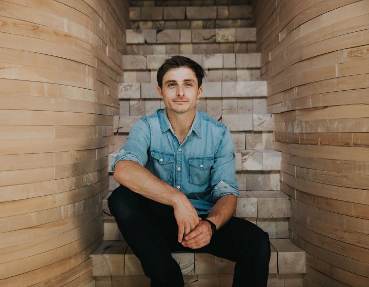 Falmouth University alumni Tom Raffield sitting on wooden steps
