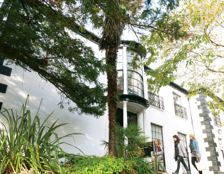 Period house on Falmouth Campus with trees and students walking by