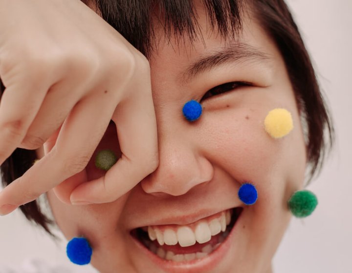 Smiling Asian girl with pompoms on her face