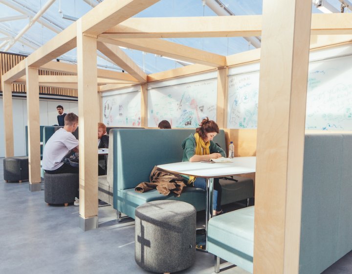 Female student studying at a table with green sofas