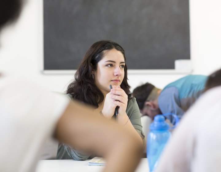 Student resting chin on her hands in lecture.