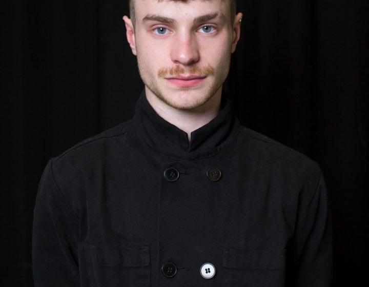 Student portrait - a white man with short hair poses in black clothing